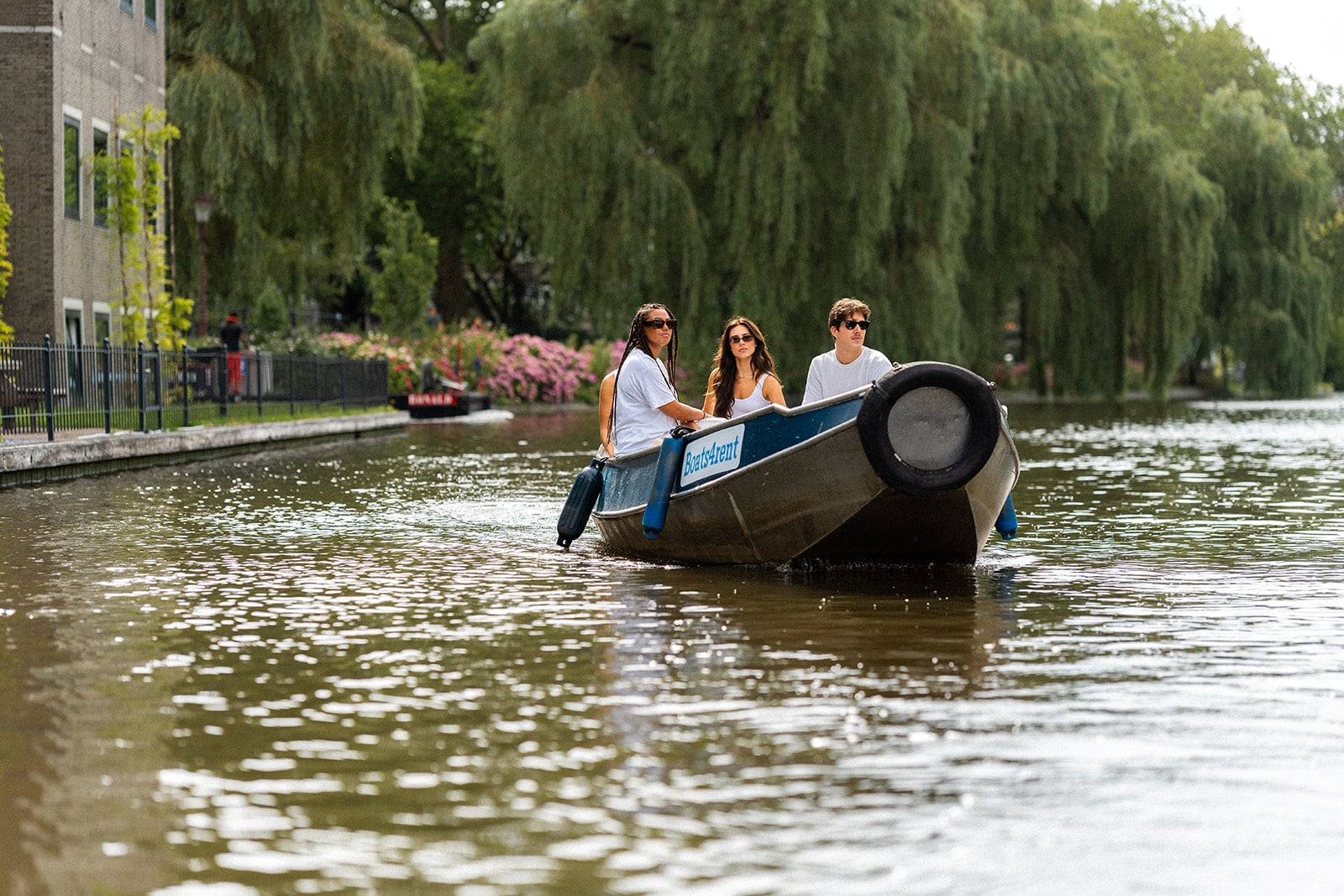 Amis profitant d'une location de bateau sur les canaux d'Amsterdam — idéal comme bon cadeau