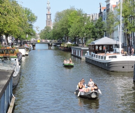 Deux bateaux naviguant le long de bateaux amarrés sur les canaux d'Amsterdam.